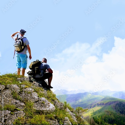 Hikers relaxing on top of a mountain and enjoying the view of valley