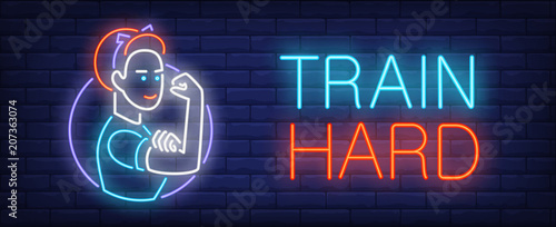 Train hard neon sign. Strong woman touching her biceps on dark brick wall. Vector illustration in neon style for motivational placard or feminism movement