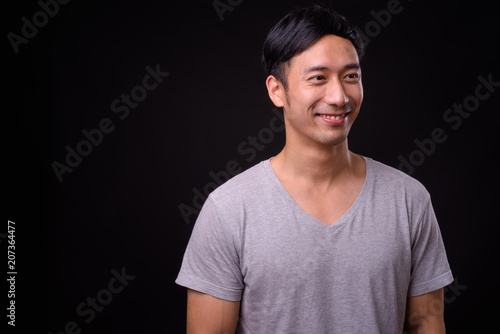 Young handsome Asian man against black background