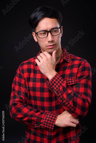 Young handsome Asian man against black background