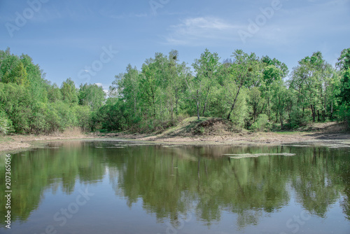 Spring  landscape with lake  green trees and blue sky with white clouds