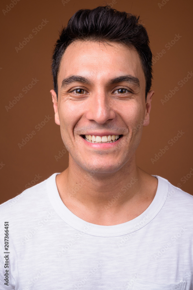 Fototapeta premium Young handsome Hispanic man against brown background