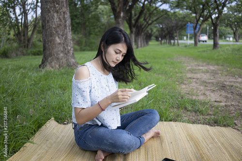 Asian women sit reading at the park.