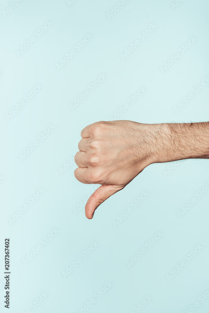 cropped shot of man doing thumb down gesture isolated on blue background cropped shot of man doing thumb down gesture isolated on blue background