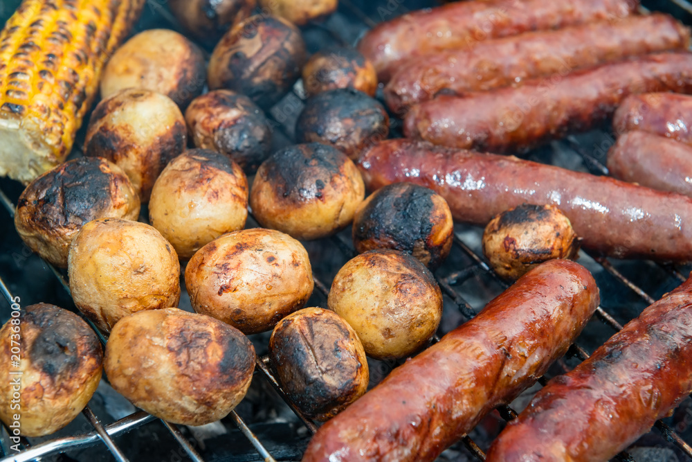 Baked potatoes, corn and sausages on a barbecue grill Baked potatoes, corn and sausages on a barbecue grill