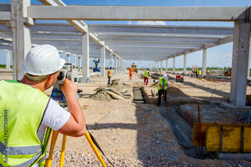 Civil engineer, geodesist is working with total station on a building site
