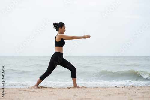 Yoga women are on the beautiful sandy beach at sunset time.