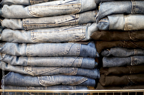 Stacks of folded denim trousers on the shelf as a background.     