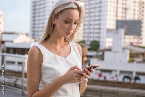 Blonde young lady typing on the phone (city life)