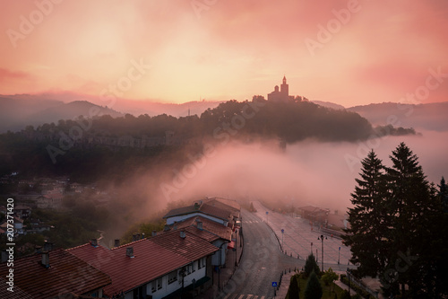 Amazing beautiful view over Tsarevets Fortress in Veliko Tarnovo, Bulgaria on a foggy sunrise in summer. photo
