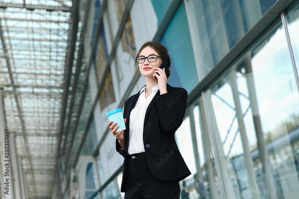 Business woman with coffe and talking on the phone near office Business woman with coffe and talking on the phone near office
