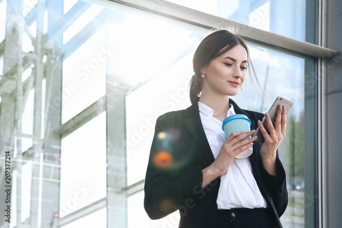 Business woman with coffe and talking on the phone near office photo