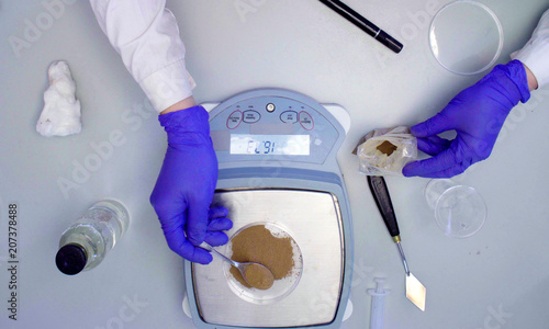 Close up hands of the scientist weighing a sample of soil in a petri dish. Ecological labarotory. photo