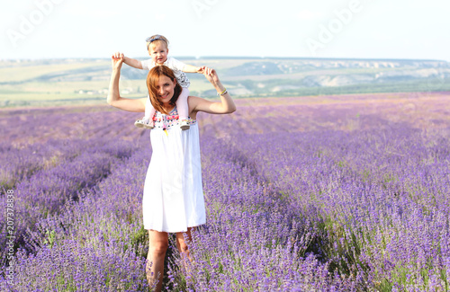 Fototapeta Naklejka Na Ścianę i Meble -  Happy little girl and her mother on lavender background. Cute baby playing in meadow field. Family holiday in summer day.
