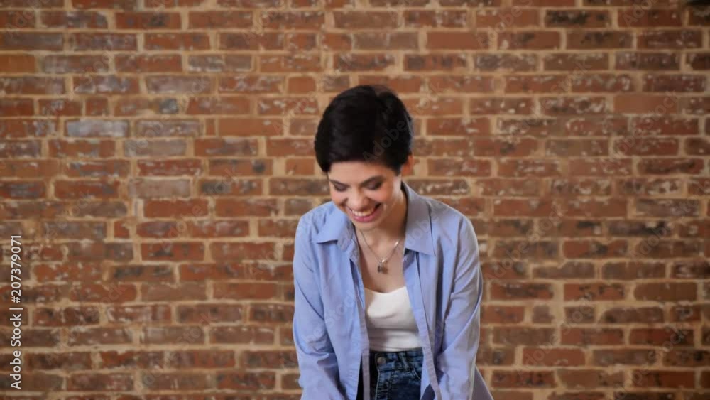 Young charming short hair girl is laughing, communication conception, brick background Young charming short hair girl is laughing, communication conception, brick background