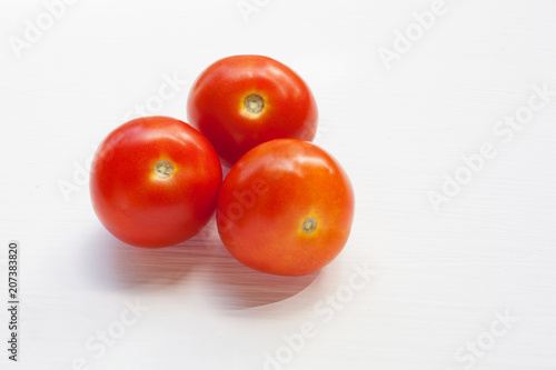 Three red  tomatoes on a white .