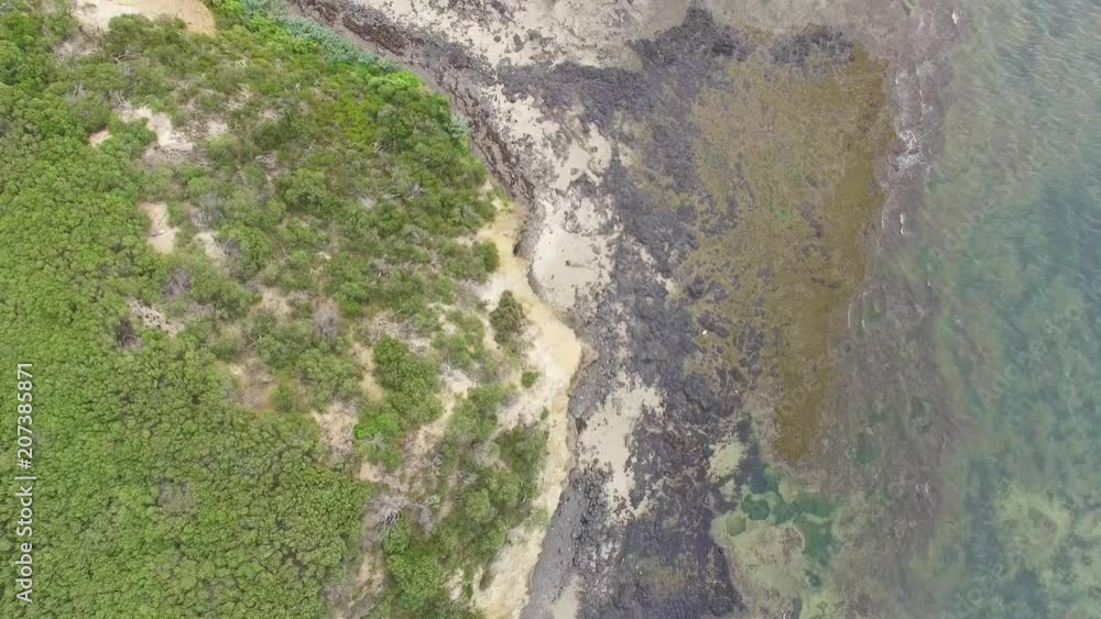 Forward flight looking down at geologic and mineral features of shallow ocean water and coastline in australia Forward flight looking down at geologic and mineral features of shallow ocean water and coastline in australia