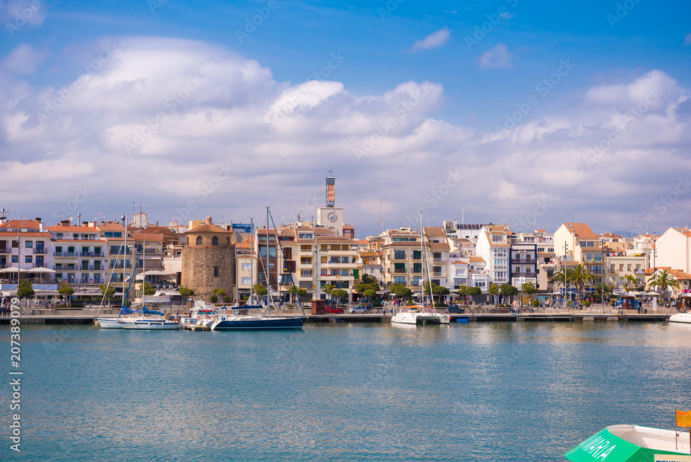 CAMBRILS, SPAIN - APRIL 30, 2017: View of port and city waterfront with Church Of Saint Peter in middle and Torre del Port. Copy space for text.