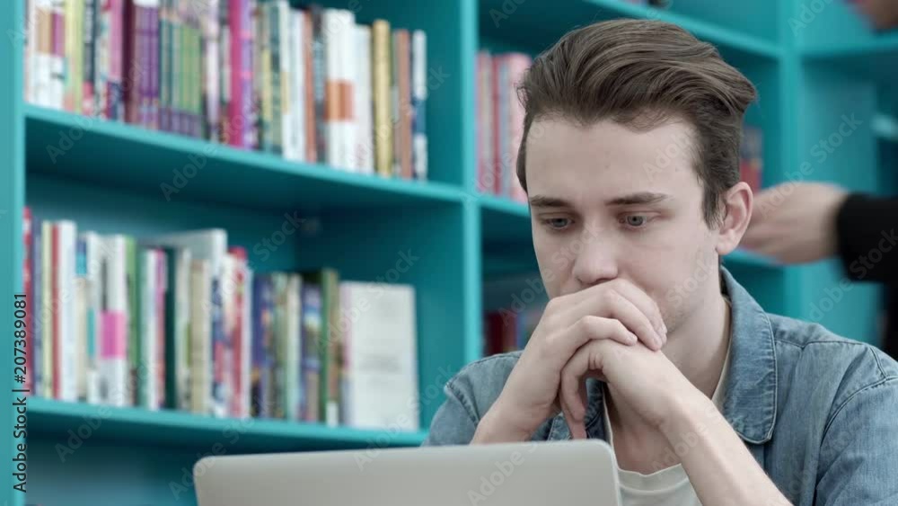 Male university student looking at laptop screen thoughtfully while doing homework. Closeup of concentrated boy trying to fulfill difficult task while studying Male university student looking at laptop screen thoughtfully while doing homework. Closeup of concentrated boy trying to fulfill difficult task while studying