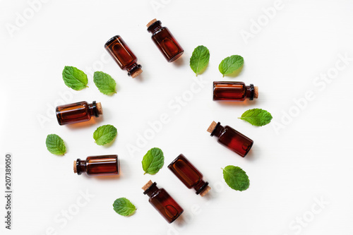 Essential oil with fresh mint leaves on white background.