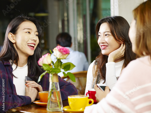 Fotografie three young asian women chatting talking in coffee shop