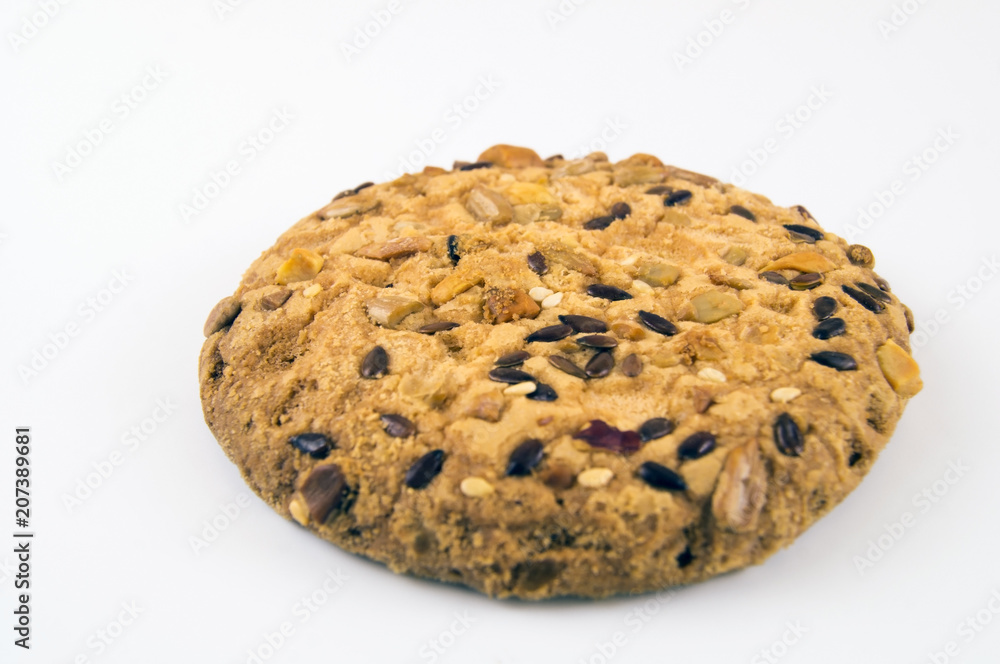 A large biscuit strewn with sesame seeds and nuts on a light background A large biscuit strewn with sesame seeds and nuts on a light background