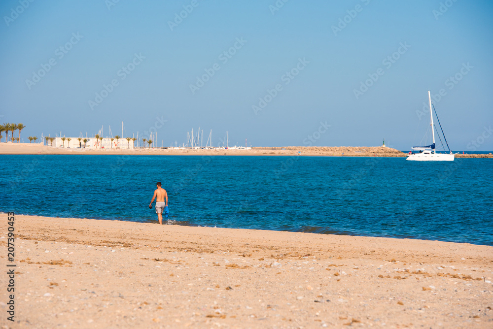 MIAMI PLATJA, SPAIN - APRIL 24, 2017: A man walks along the sandy beach in the distance. Copy space for text.