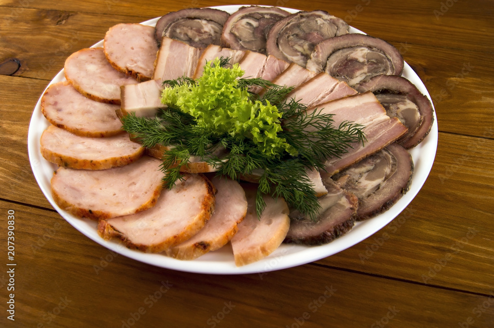 Bacon, roll and sausage, decorated with salad and dill on a wooden background Bacon, roll and sausage, decorated with salad and dill on a wooden background