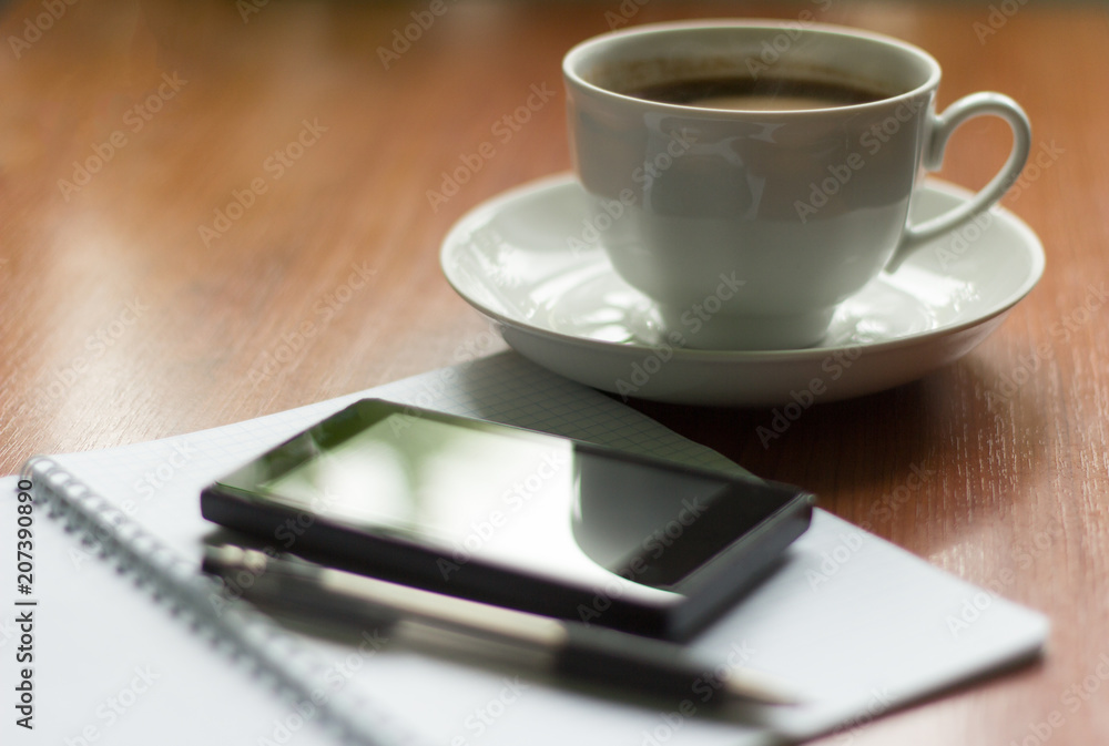morning hot coffee, notebook and phone on the table morning hot coffee, notebook and phone on the table
