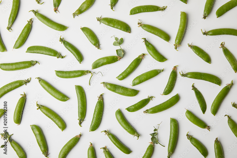 top view of ripe pea pods spilled on white surface top view of ripe pea pods spilled on white surface