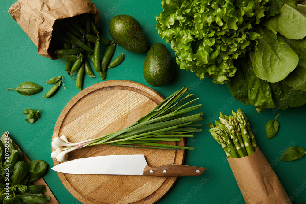 top view of different ripe vegetables with wooden cutting board and knife on green surface - obrazy, fototapety, plakaty 