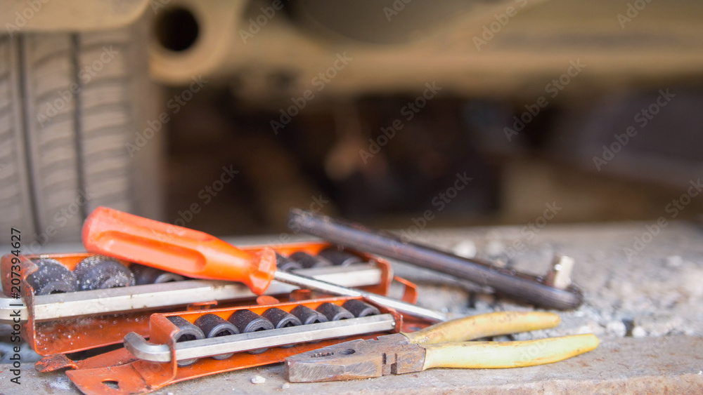 Fototapeta premium Set of tools in front of man underneath a car unscrewing details from under tray