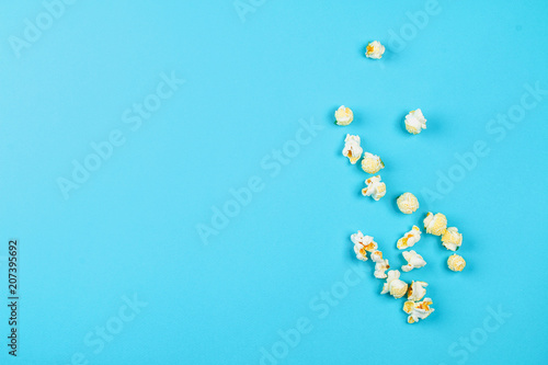 Box of popcorn spilled on blue background.