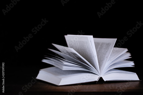 open book lying on a table on a dark background
