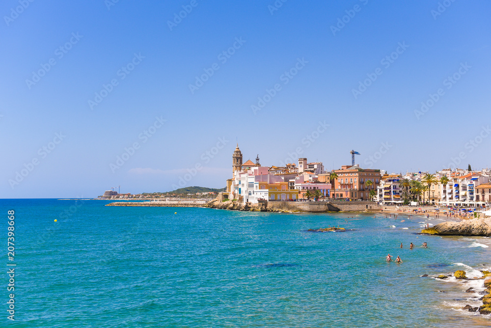SITGES, CATALUNYA, SPAIN - JUNE 20, 2017: View of the historical center and the ñhurch of Sant Bartomeu and Santa Tecla. Copy space for text. Isolated on blue background.