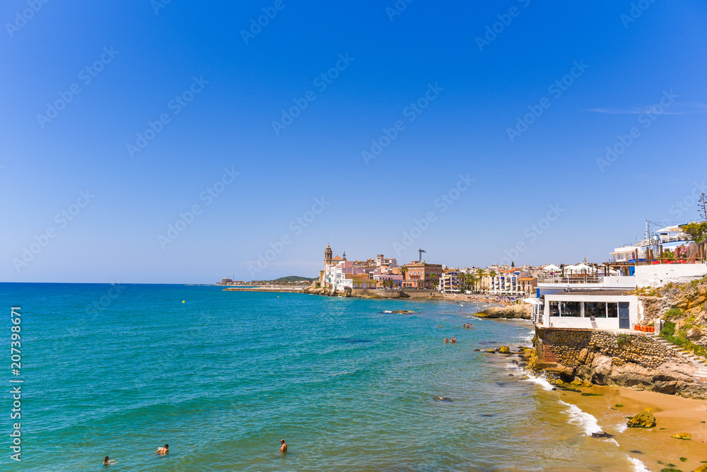 SITGES, CATALUNYA, SPAIN - JUNE 20, 2017: View of the historical center and the ñhurch of Sant Bartomeu and Santa Tecla. Copy space for text. Isolated on blue background.