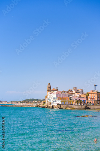 SITGES, CATALUNYA, SPAIN - JUNE 20, 2017: View of the historical center and the ñhurch of Sant Bartomeu and Santa Tecla. Copy space for text. Isolated on blue background. Vertical.