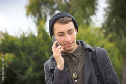 Young man using mobile phone in the city. Hipster and student lifestyle. photo