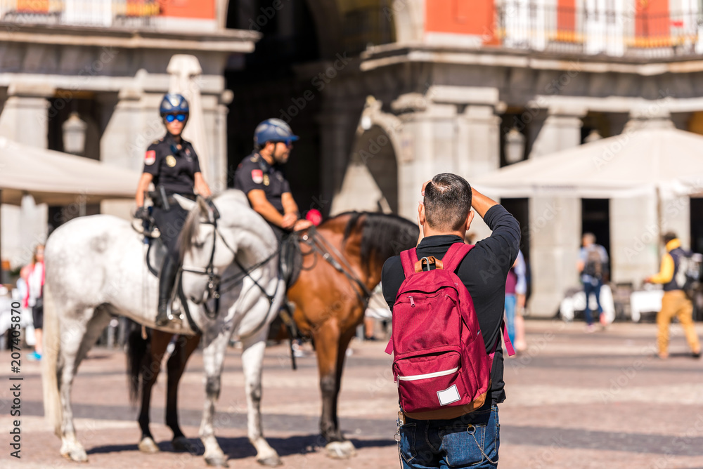 MADRID, SPAIN - SEPTEMBER 26, 2017: A man photographs the mounted police in the square of the Royal Palace building. MADRID, SPAIN - SEPTEMBER 26, 2017: A man photographs the mounted police in the square of the Royal Palace building.