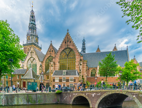 Amsterdam, The Netherlands May 27 2018 - Tourists passing the Old Church (oude Kerk) at the Oude zijds Voorburgwal in the old part of Amsterdam photo