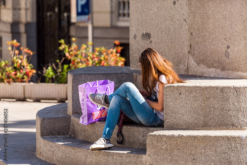 MADRID, SPAIN - SEPTEMBER 26, 2017: The girl is sitting on the steps near the building. Copy space for text.