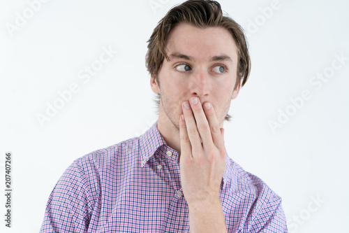 Bild auf Leinwand Curious young man covering mouth while listening to gossip