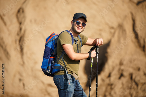 Image of sports man with backpack and walking sticks