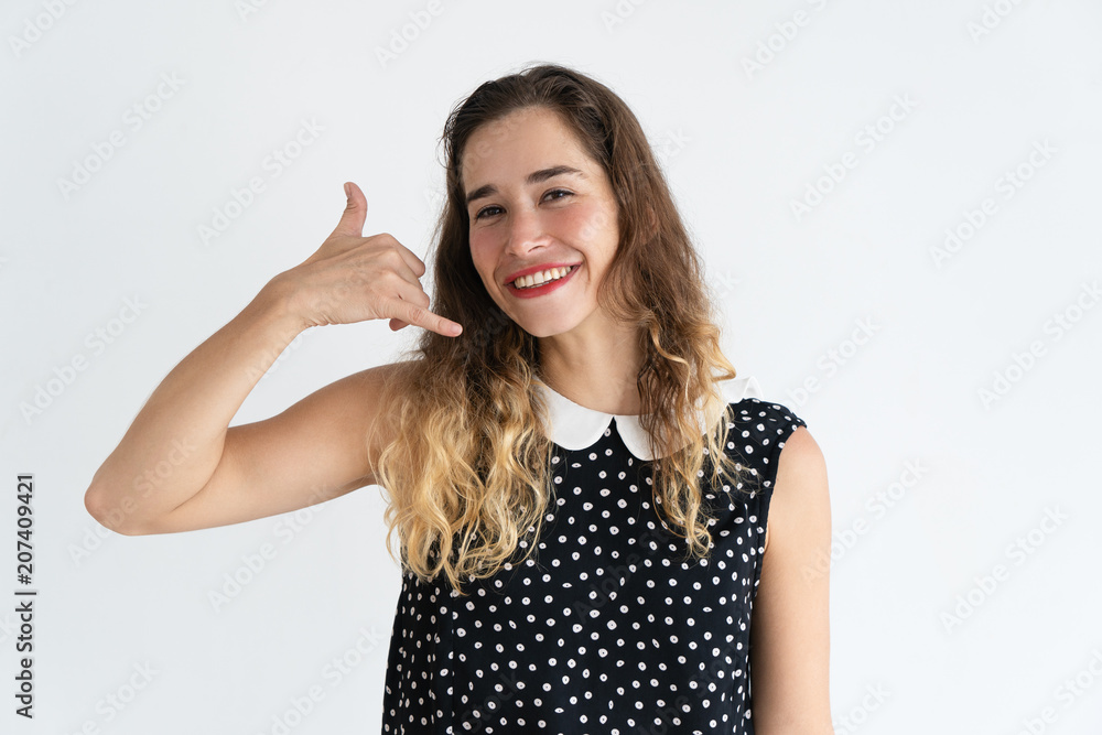 Smiling pretty young woman making call me gesture and looking at camera. Communication concept. Isolated front view on white background. Smiling pretty young woman making call me gesture and looking at camera. Communication concept. Isolated front view on white background.