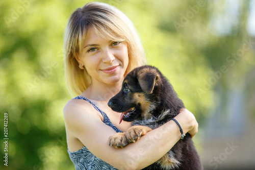 Young smiling woman holding small puppy of german shepherd photo