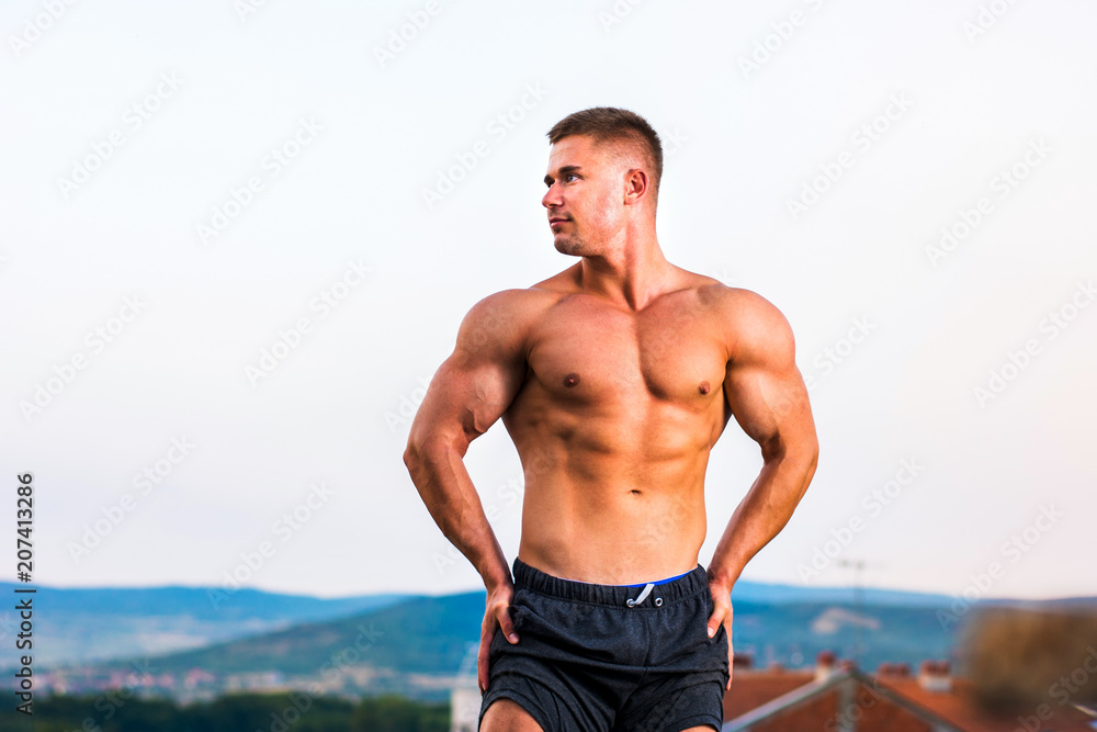 Obraz premium Man showing shaped muscles on a rooftop