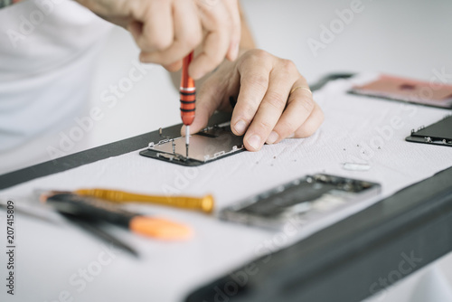 Electronics repair service. Technician disassembling smartphone for inspecting.