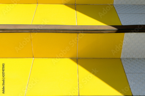 Abstract bright detail in minimal style architecture background - stairs of ceramic tiles of warm yellow  illuminated by sun with darkened corners. Detail of colorful modern building..