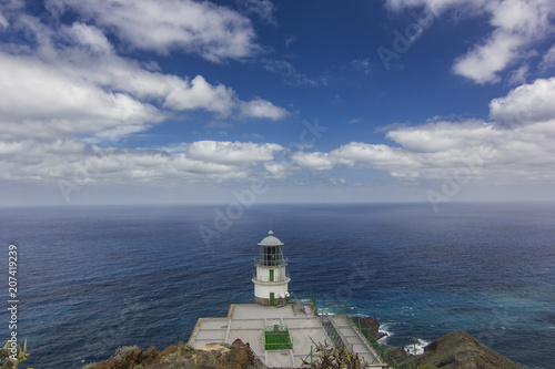 white lighthouse with view on ocean and blue sky with clouds