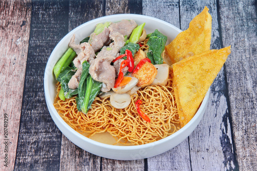 Crispy noodle and crisy wonton in Chinese kale soup with softed pork , fried softed tofu ,carrot,mushroom and red chili. photo